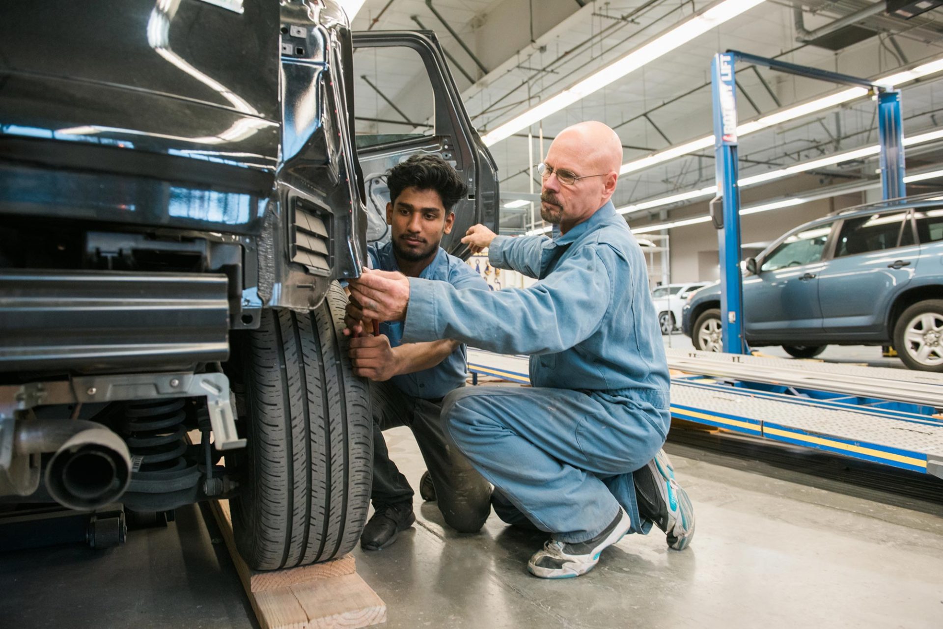 two mackins employees repairing a car side fender